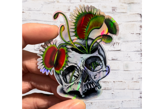 Sticker design of a skull with Venus flytrap-like mouth on a hand against a wooden background