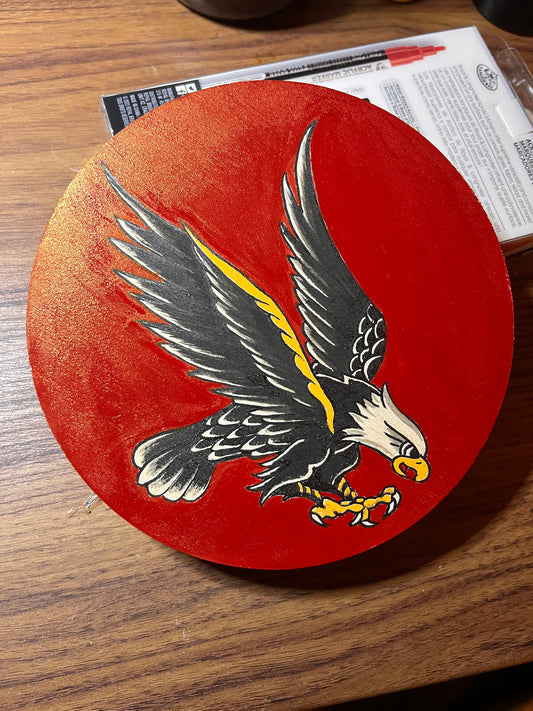 An eagle design on a red background, placed on a wooden surface.
