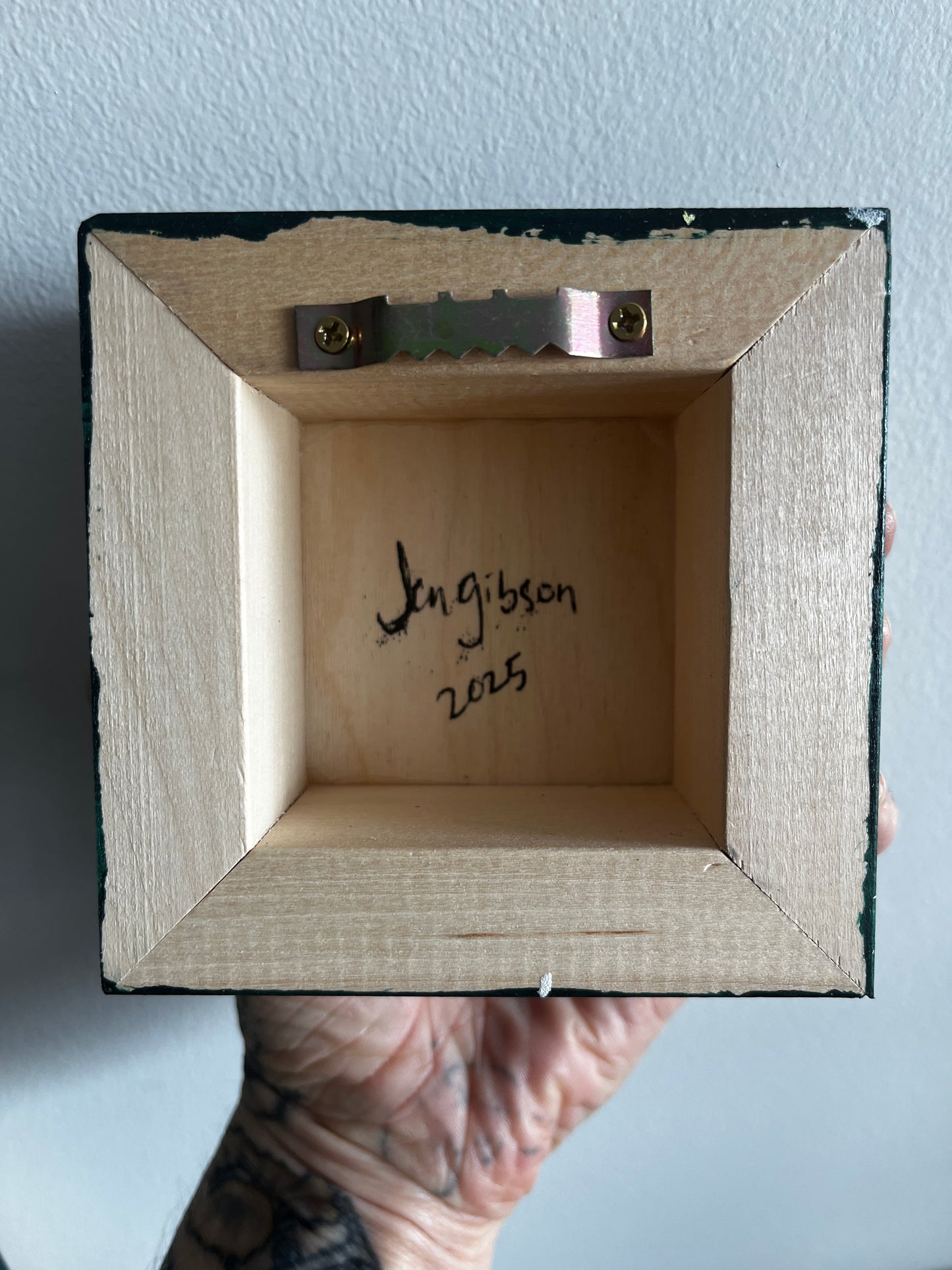 Wooden box with a signature and date on a light blue background