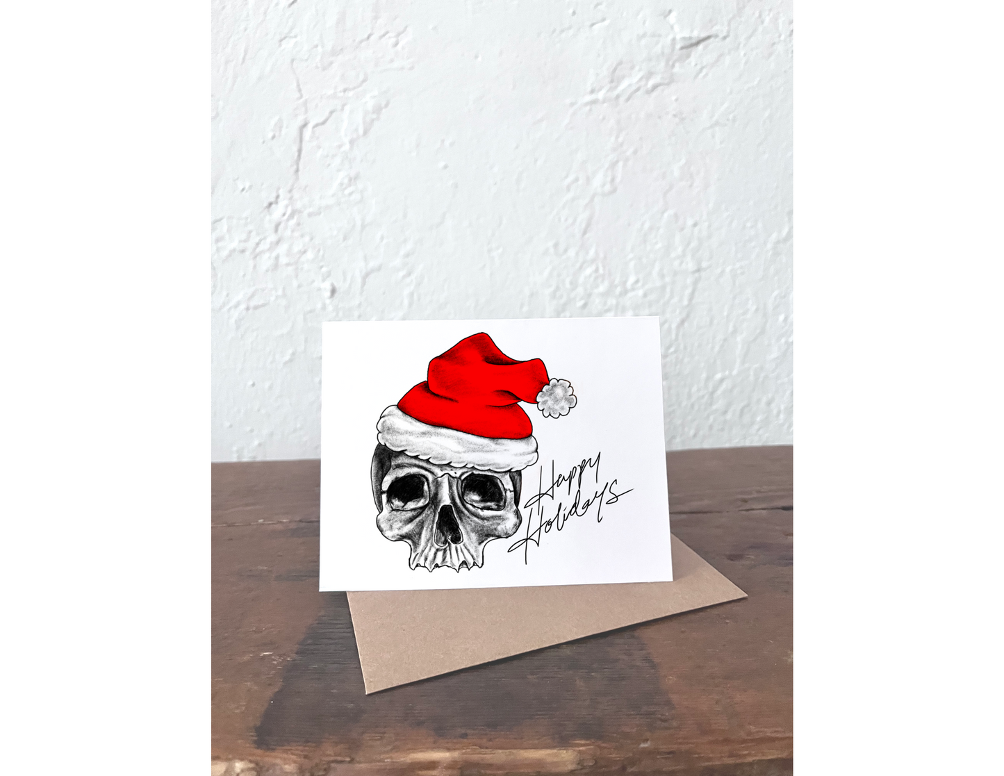 Card with a skull wearing a Santa hat and 'Happy Holidays' text on a white background.