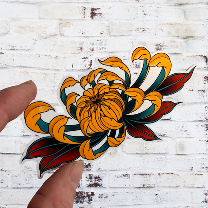 Colorful tattoo-style flower design held by a hand against a white wooden background