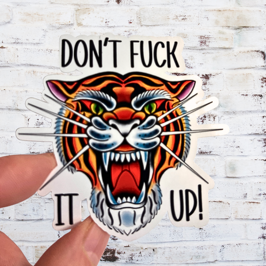 Sticker with a tiger design and text held against a white wooden background