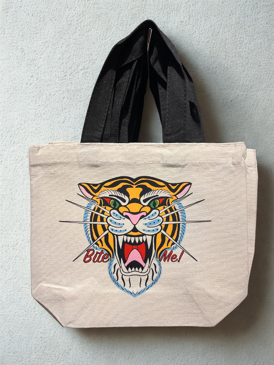 Beige tote bag with a tiger design and ' Bite Me!' text on a light gray background