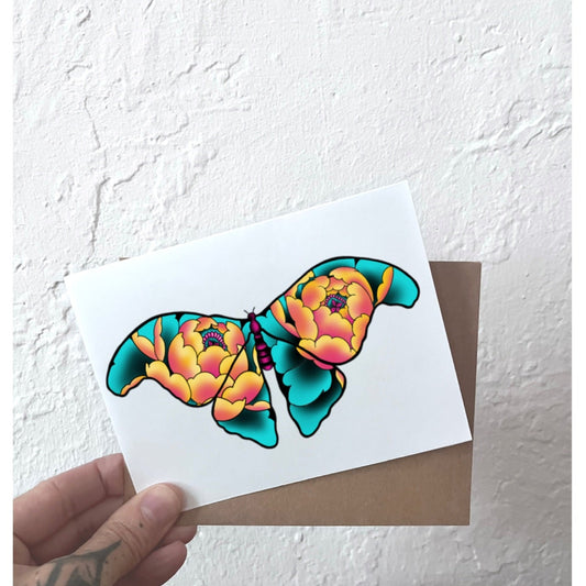 Greeting card with a colorful butterfly design held against a white wall.