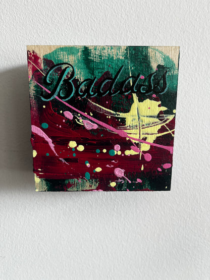 Abstract painting with 'Badass" text & splashes of colour on a textured wall