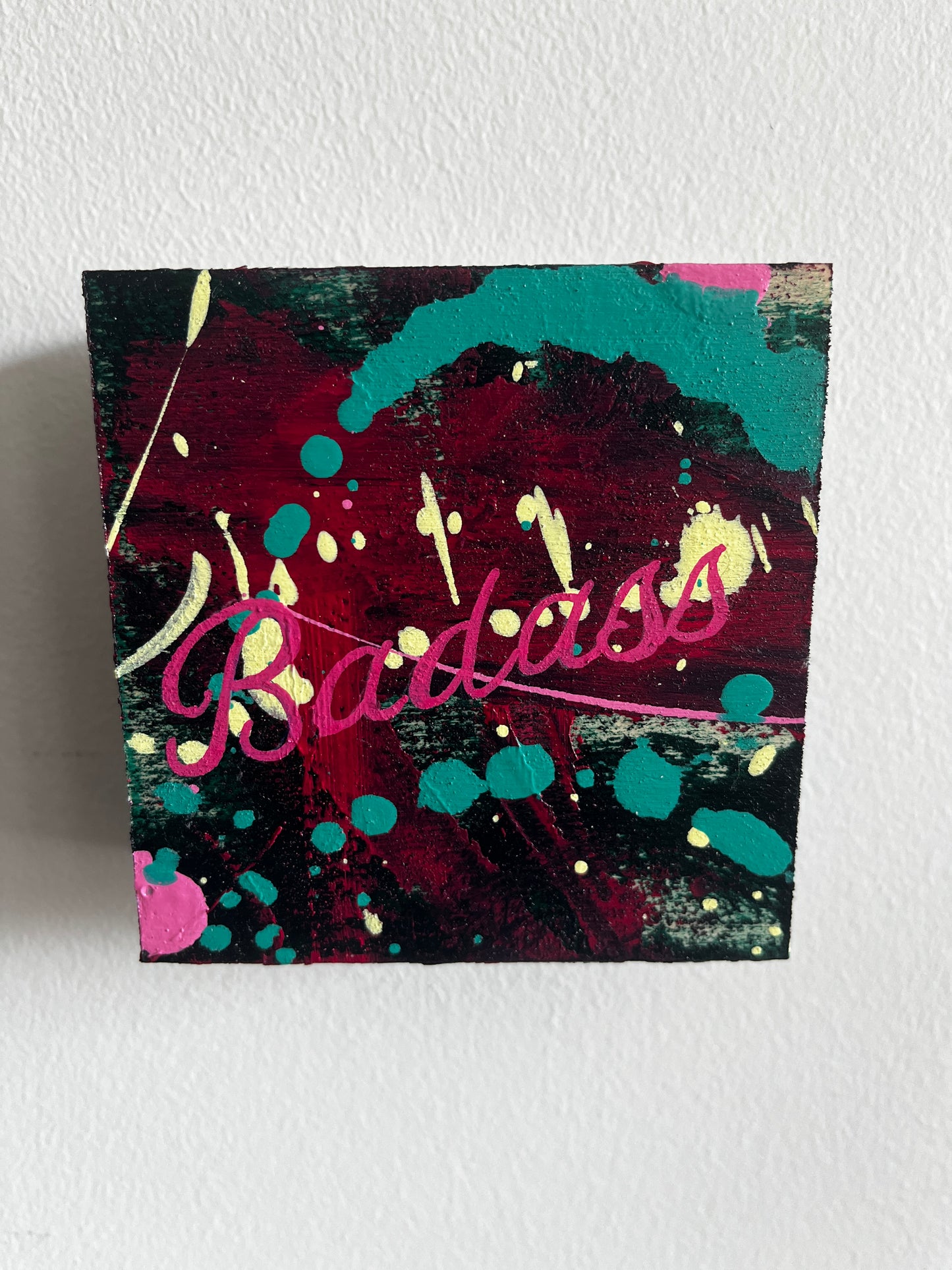 Colorful abstract painting with the word 'Badass' on a white wall