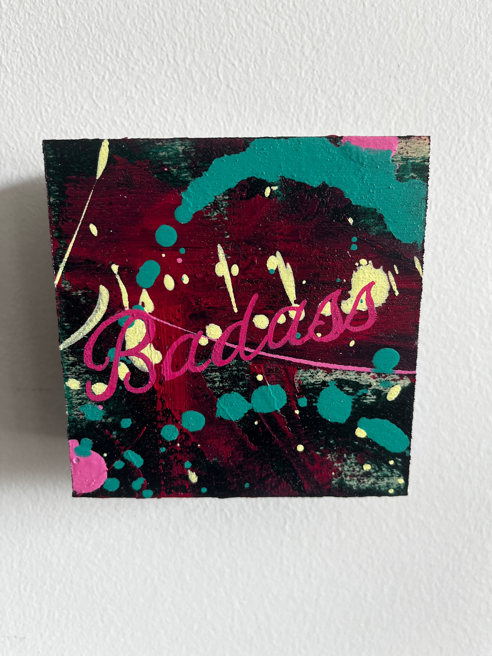 Colorful abstract painting with the word 'Badass' on a white wall