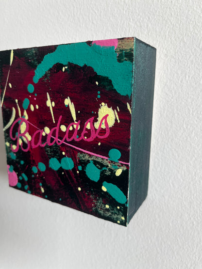 Colorful abstract painting with 'Badass' text on a textured white background