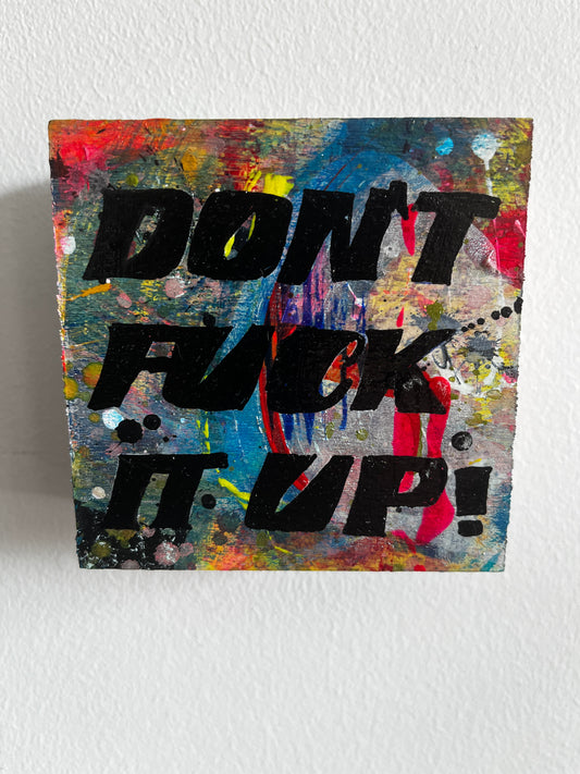 Abstract art piece with colorful splashes and bold black text on a white wall.