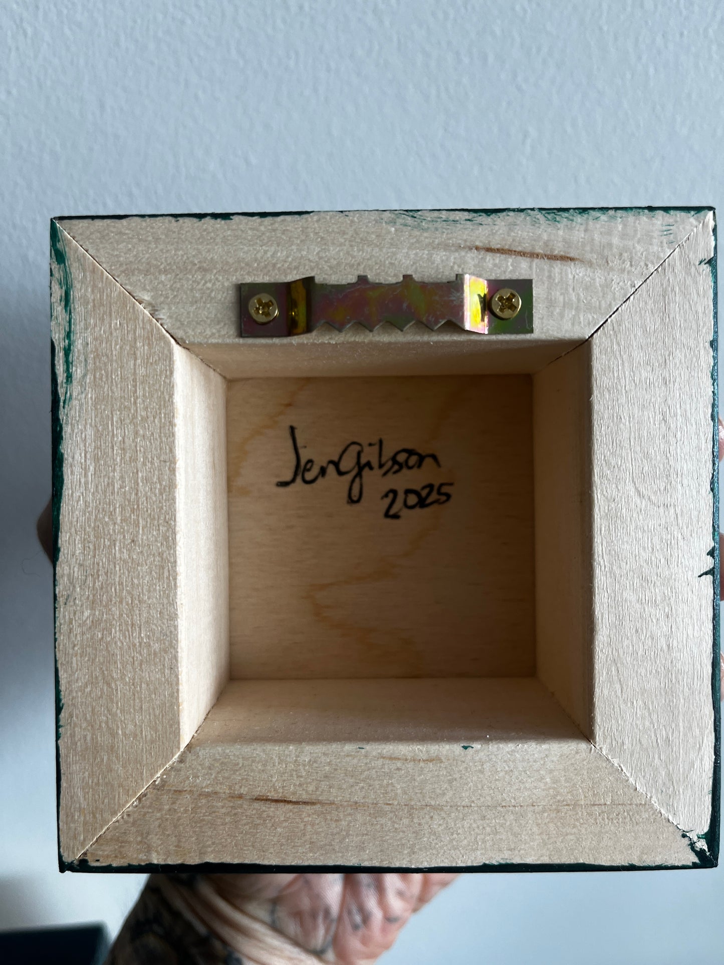 Wooden box with a signature and date on a light blue background