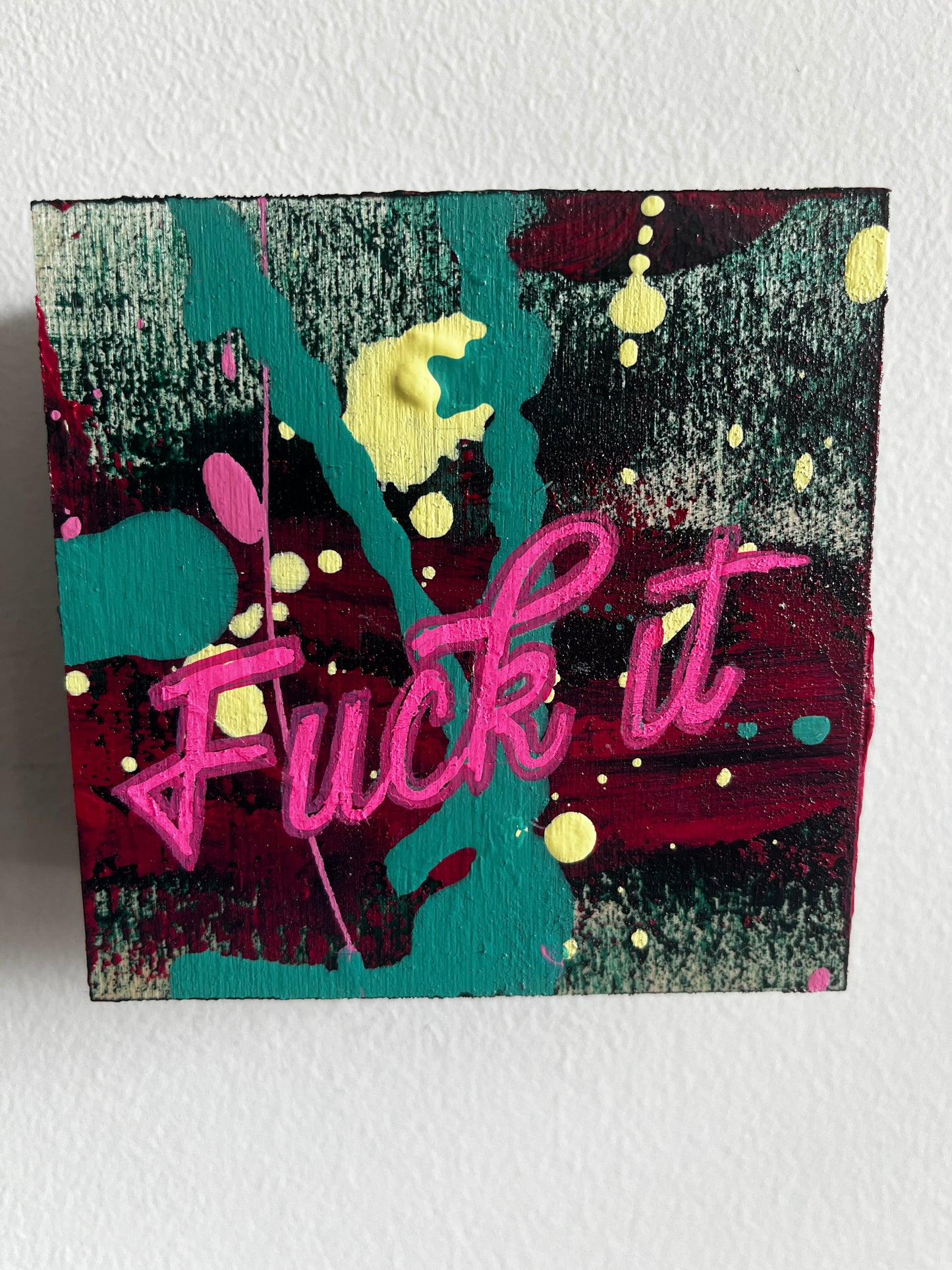 Abstract artwork with pink text and colorful splashes on a textured surface