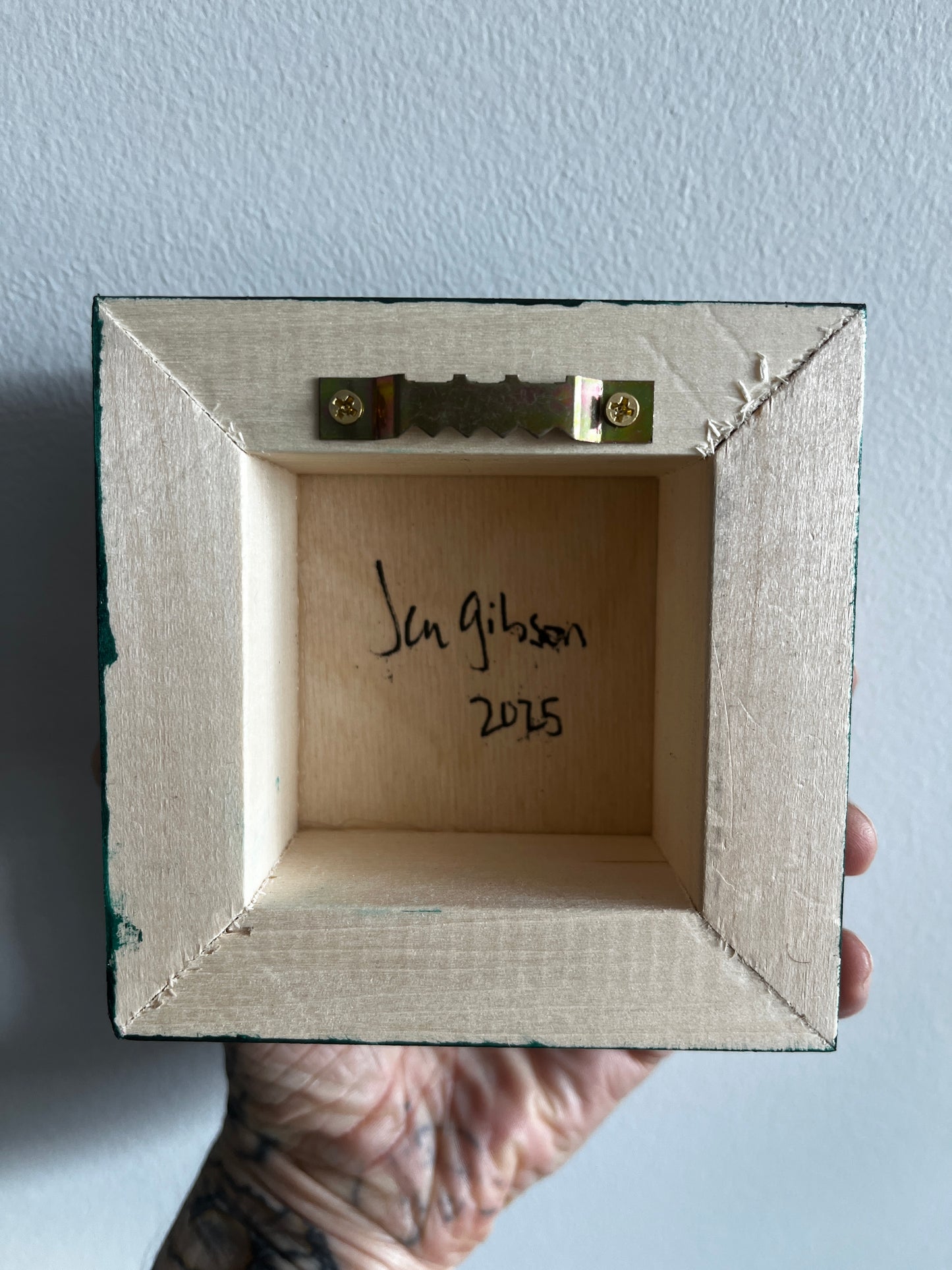 Wooden box with a signature and date on a light blue background