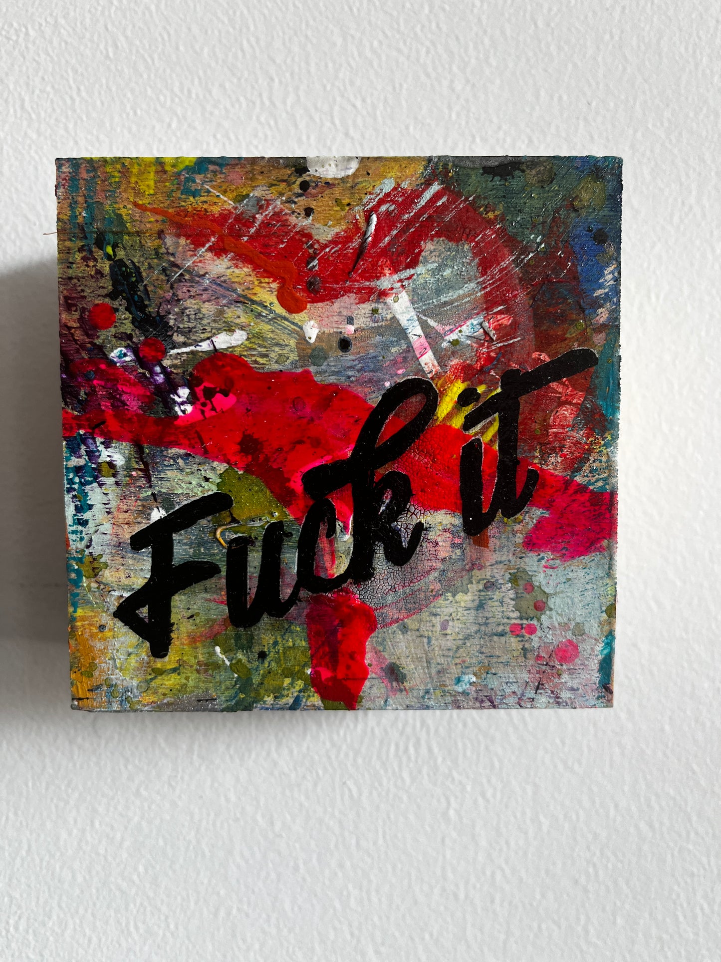 Abstract painting with colorful splashes and the word 'Fuck it' in black.