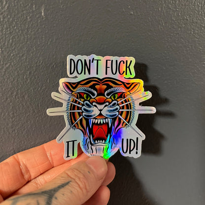 Holographic sticker with a tiger design and text held against a dark background