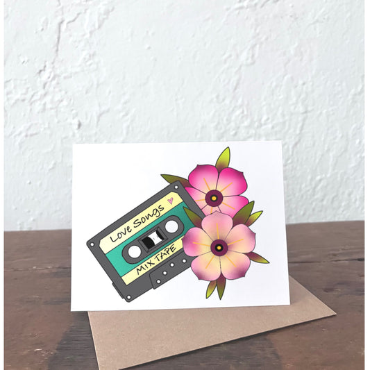 Greeting card with cassette tape and flowers on a wooden surface