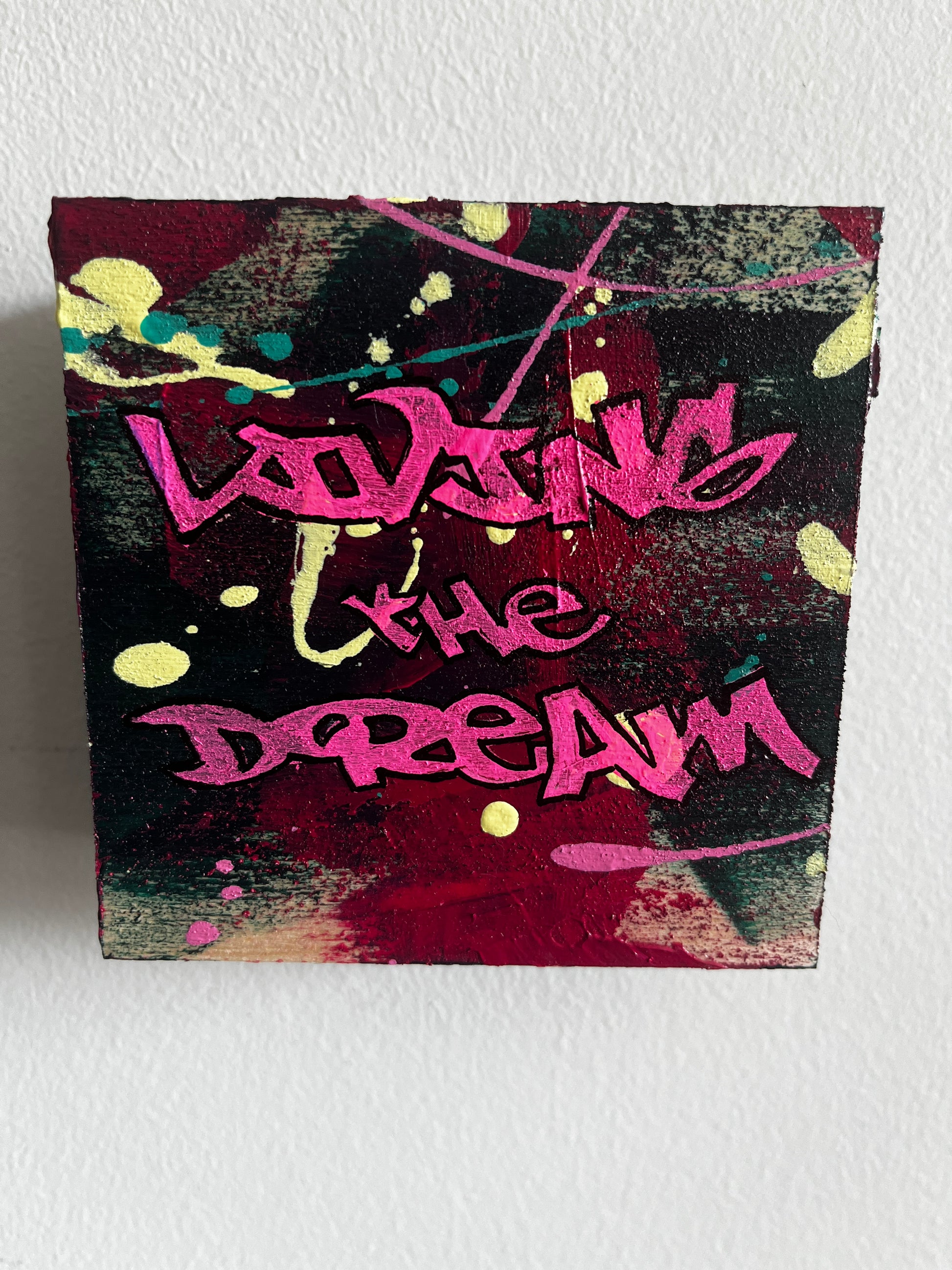 Graffiti-style artwork with pink text on a textured surface