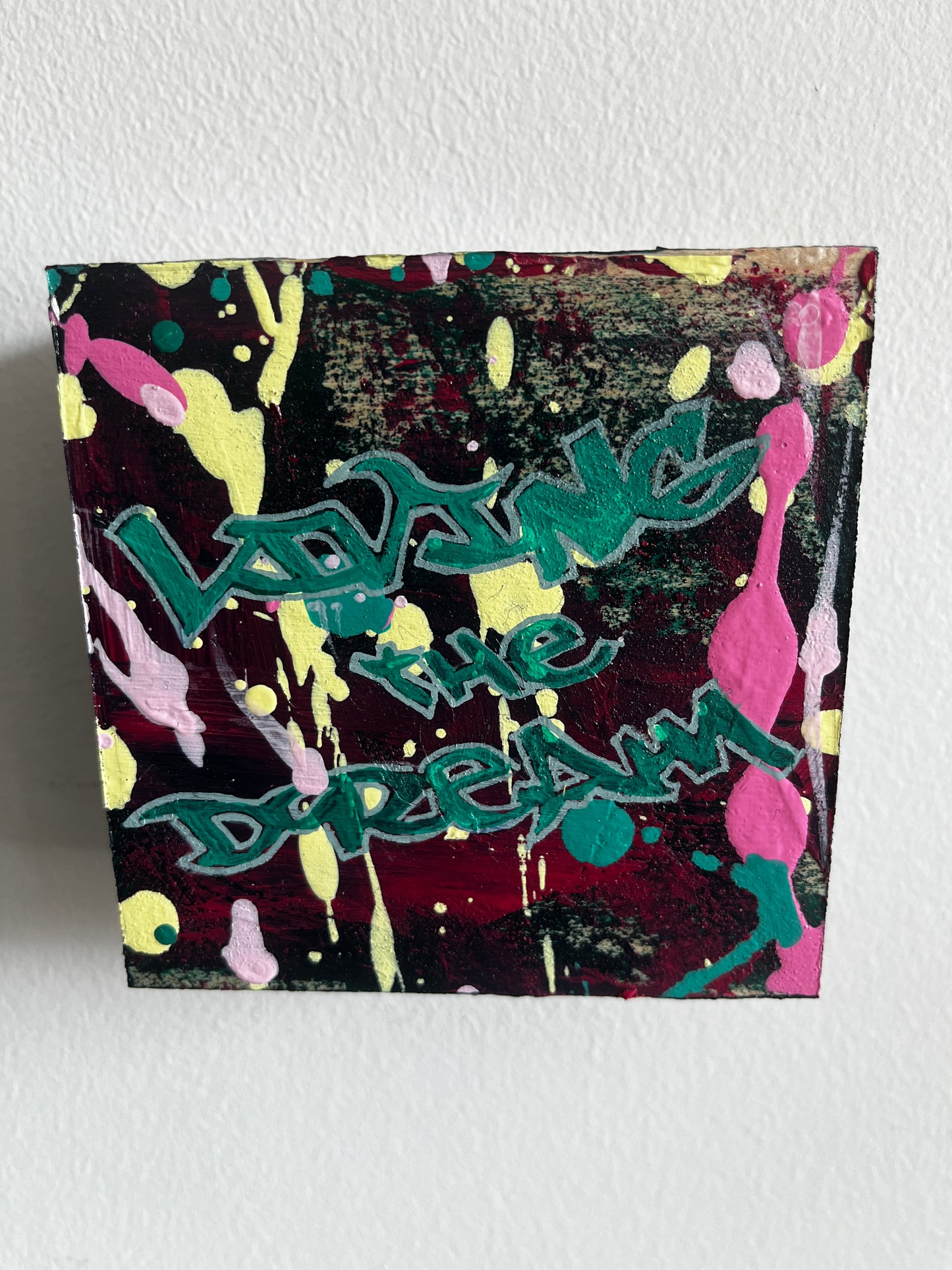 Colorful abstract painting with text on a textured wall