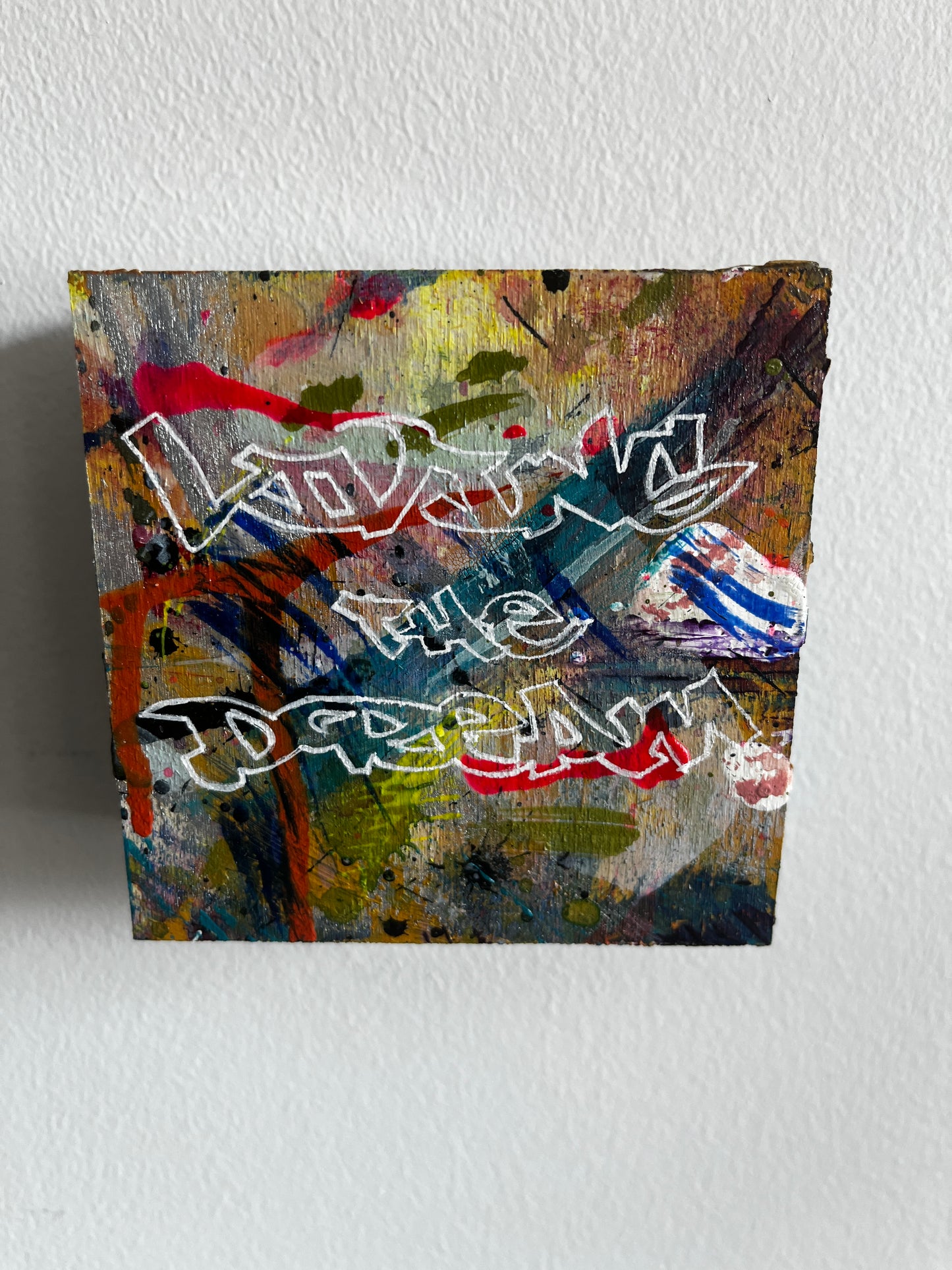 Abstract artwork with colorful text on a textured wall