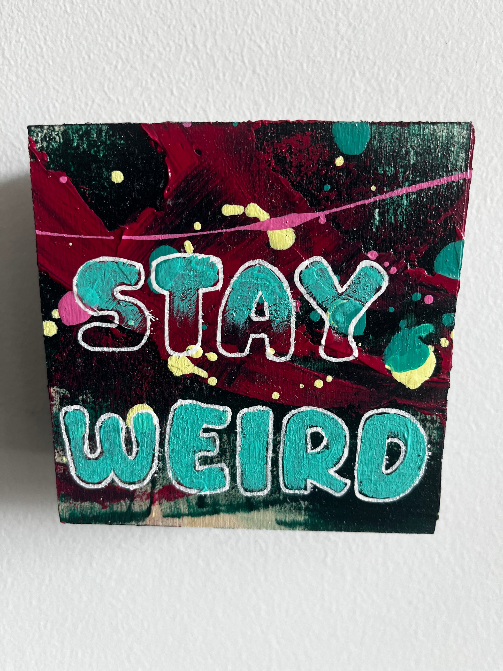 Colourful abstract painting with 'Stay Weird' text on a textured white background