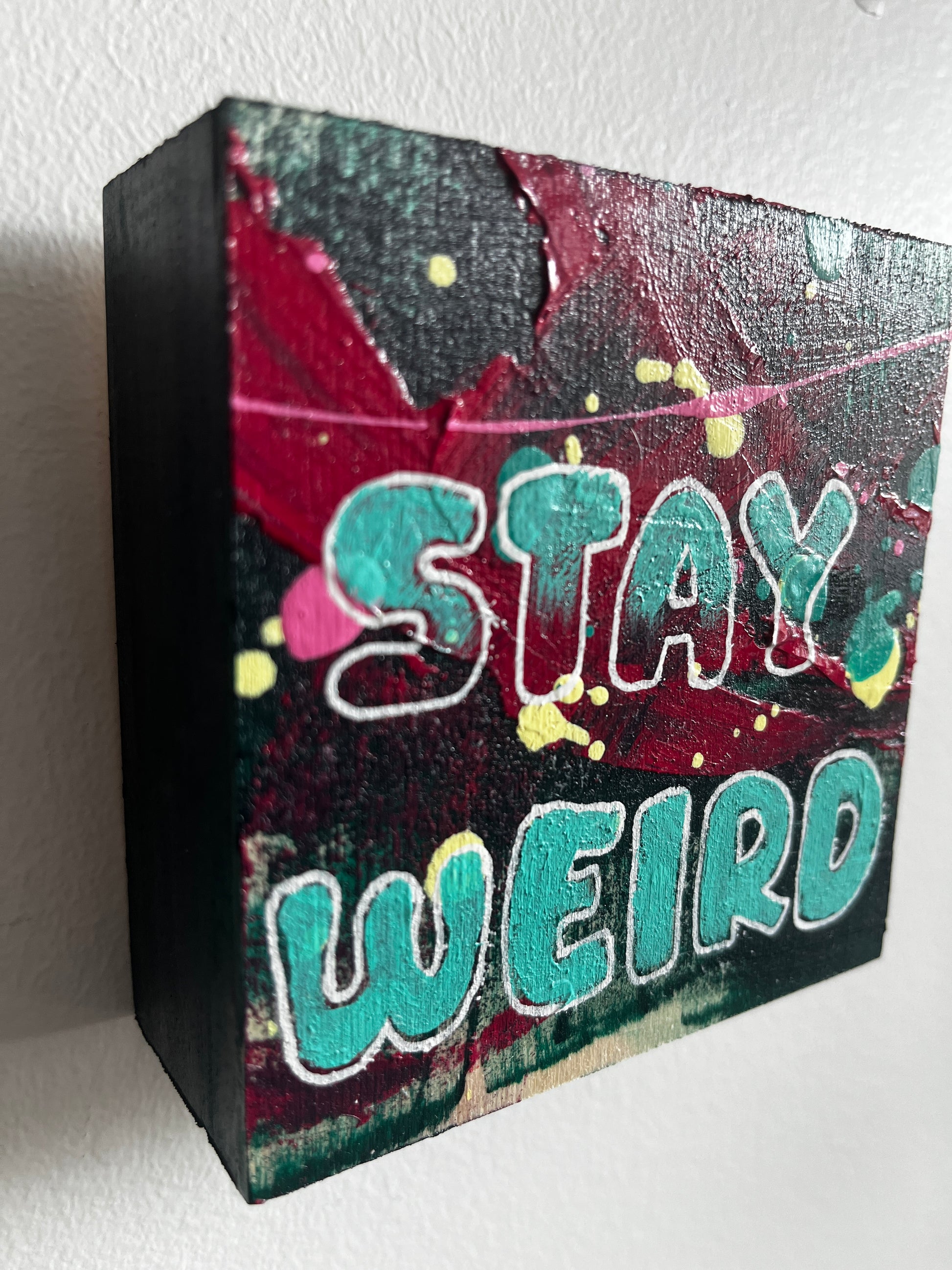 Colourful square painting with 'Stay Weird' text on a white background