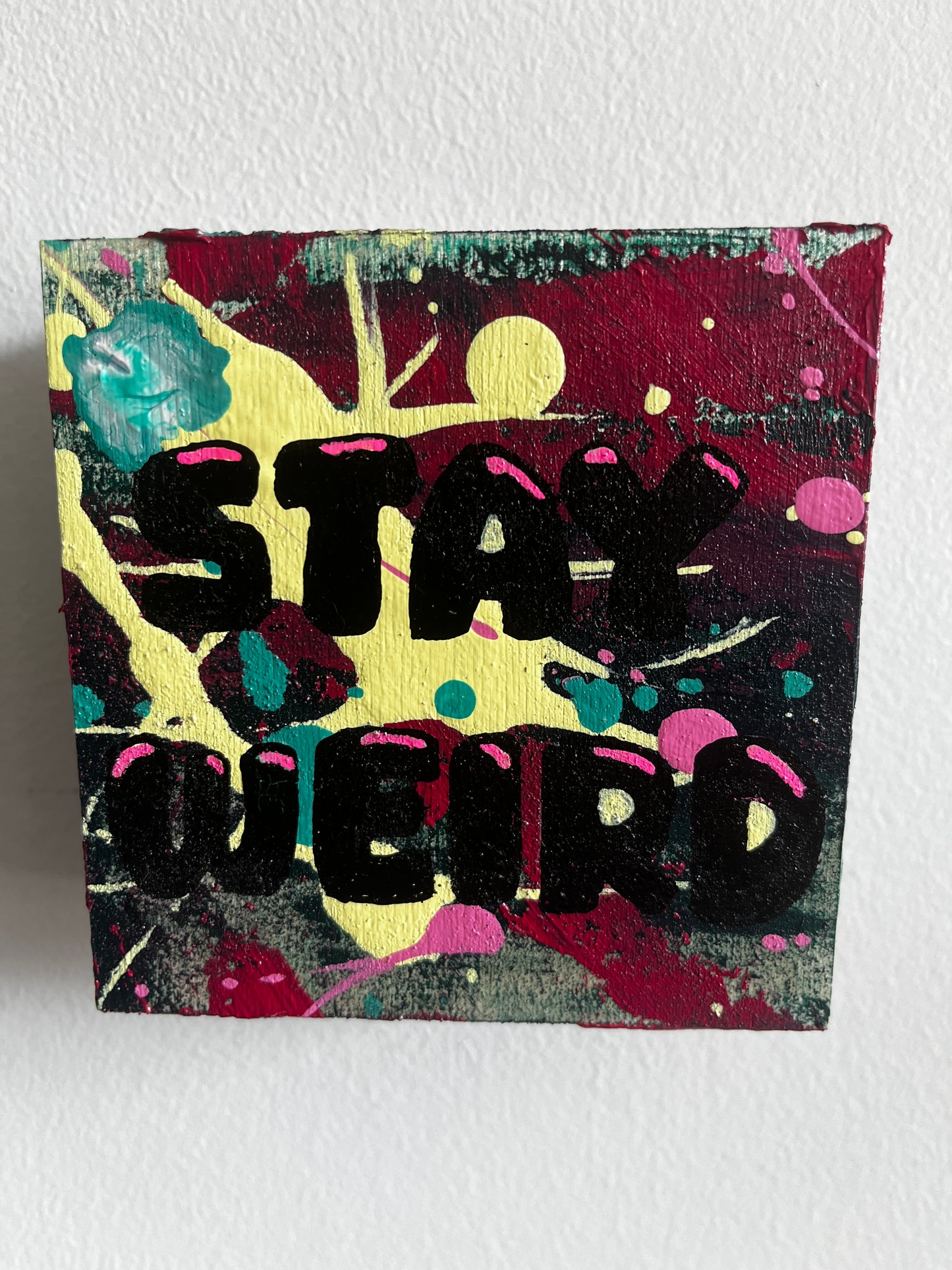 Abstract art piece with black text "Stay Weird" on a colourful background