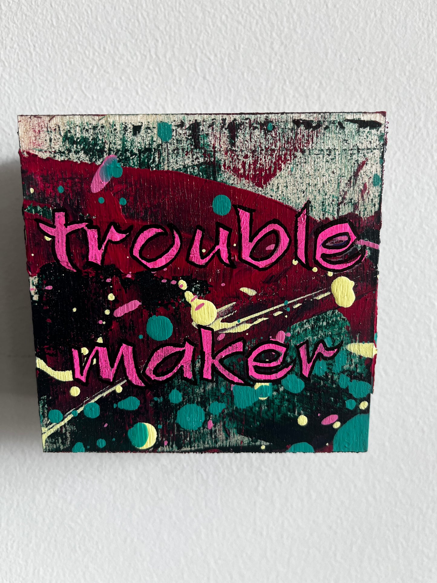 Colourful abstract design and text saying Trouble maker on a light grey background