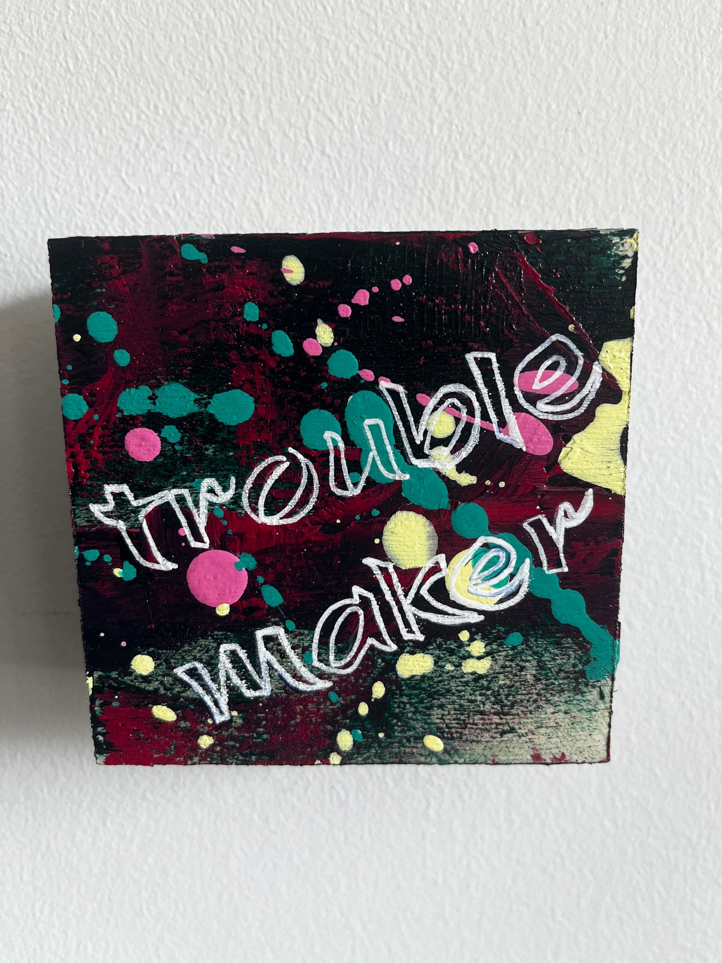 Abstract artwork with colorful text and shapes on a textured surface