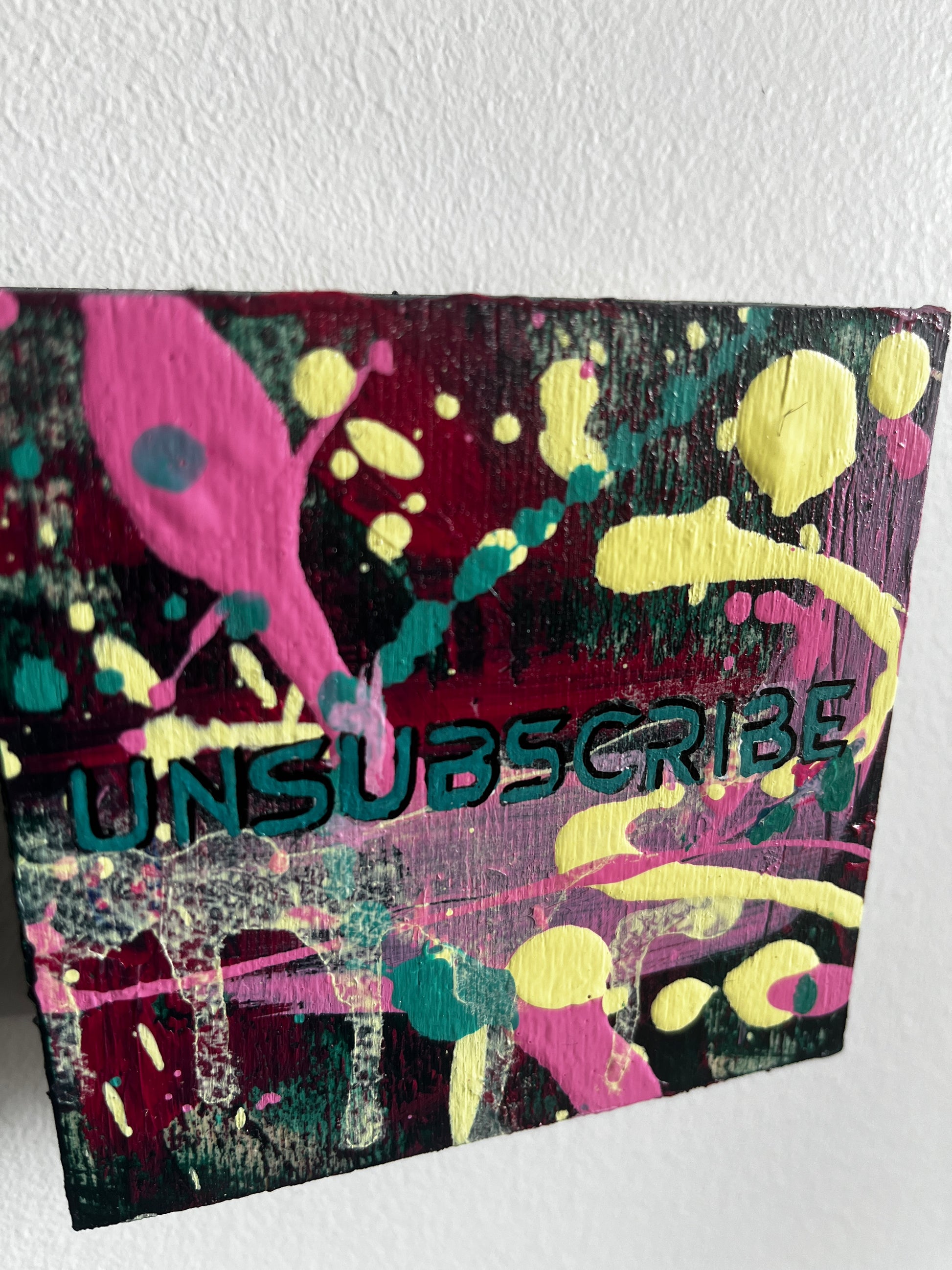 Colorful abstract poster with splashes and 'Unsubscribe' text on a white background