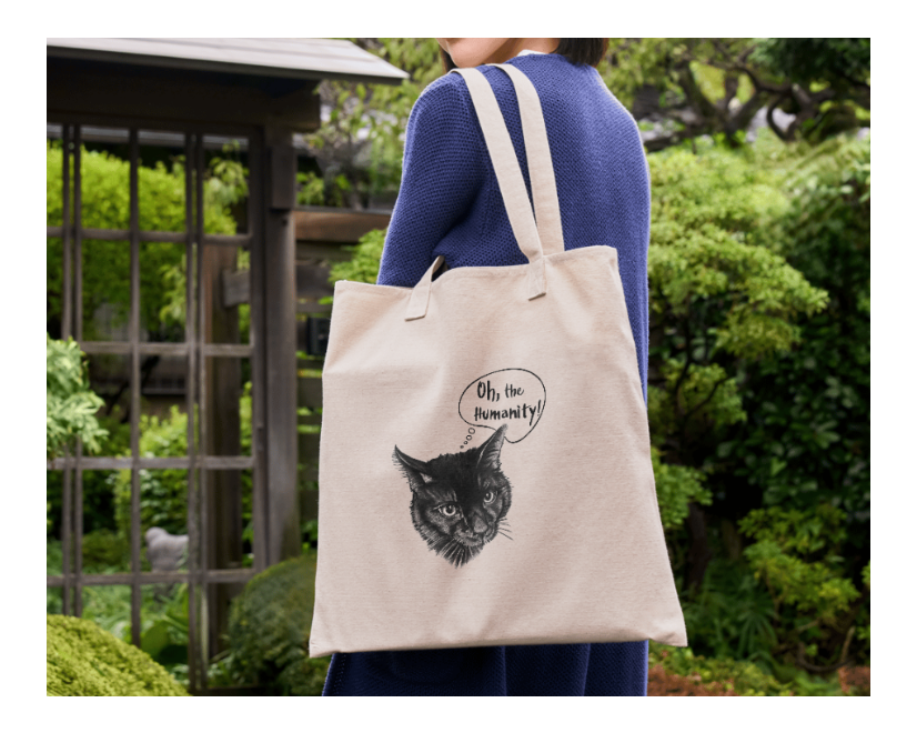 Woman holding a tote bag with a black cat design in a garden setting