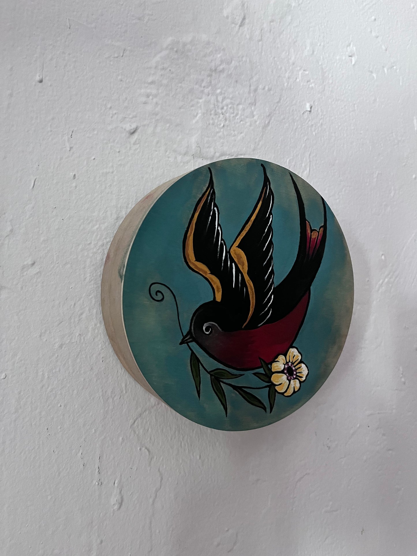 Round decorative item with a bird design on a white background