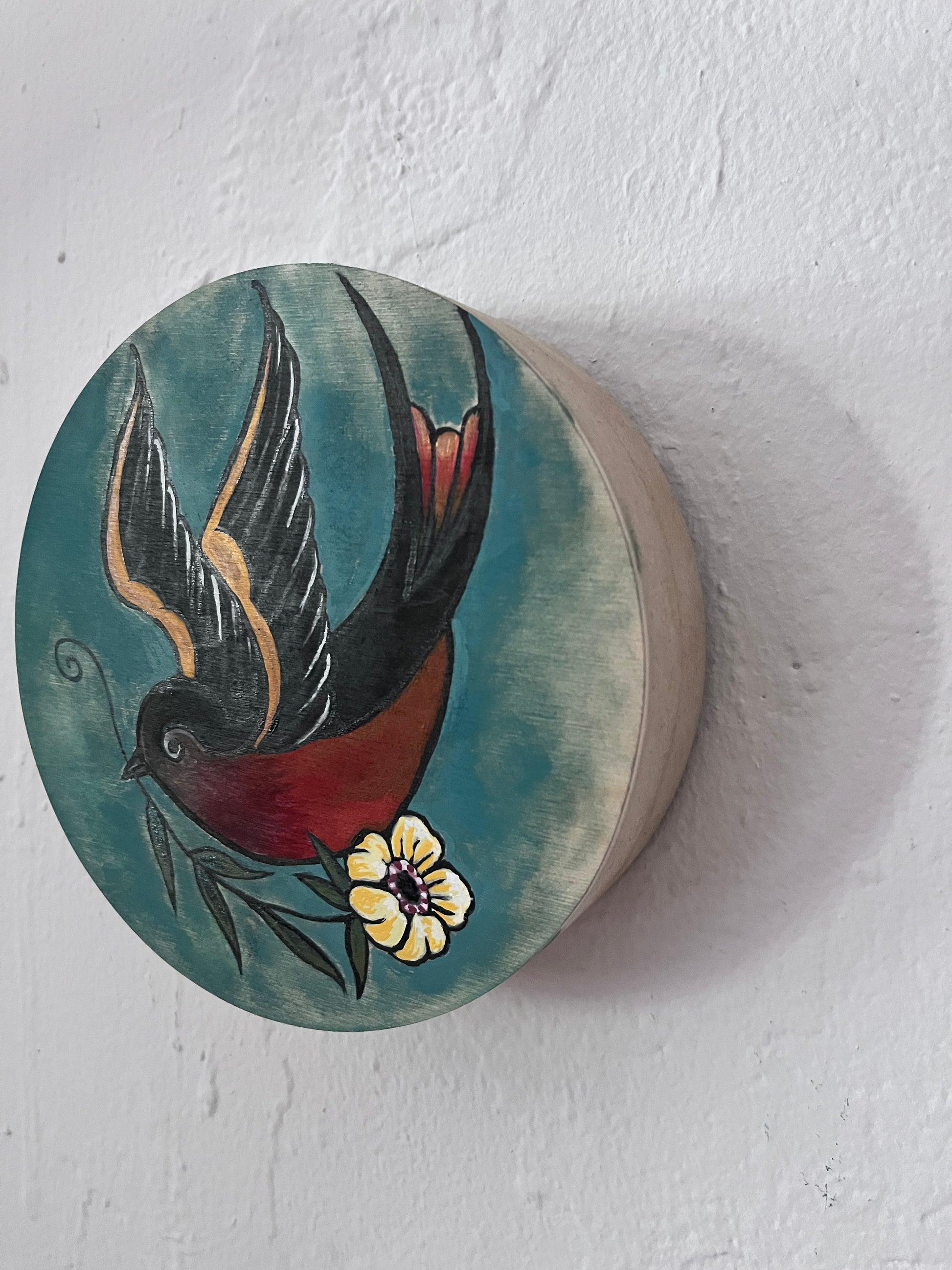 Decorative wooden panel with a painted bird and flower design on a white background
