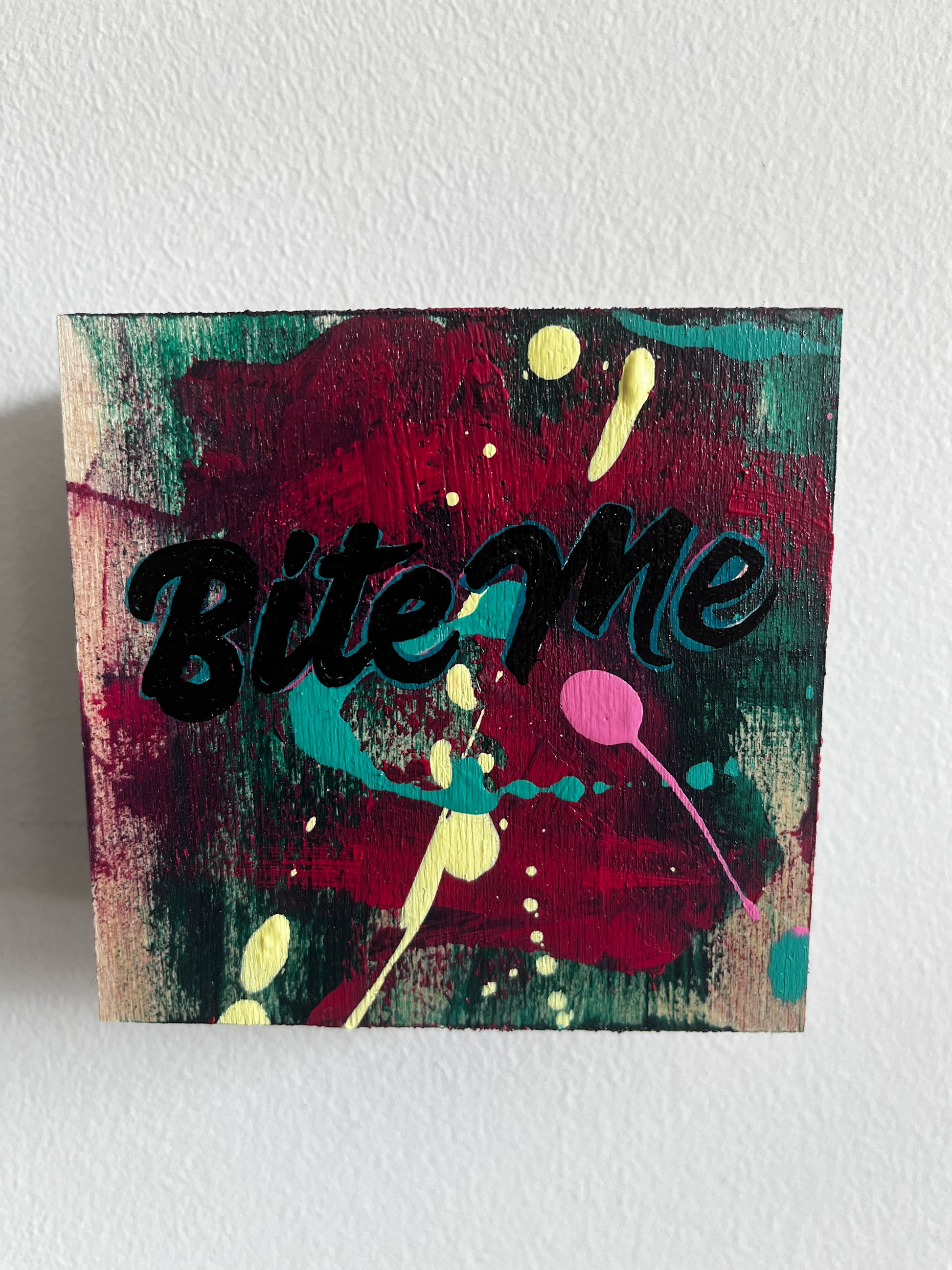 Colorful abstract painting with the word 'Bite Me' on a textured white background