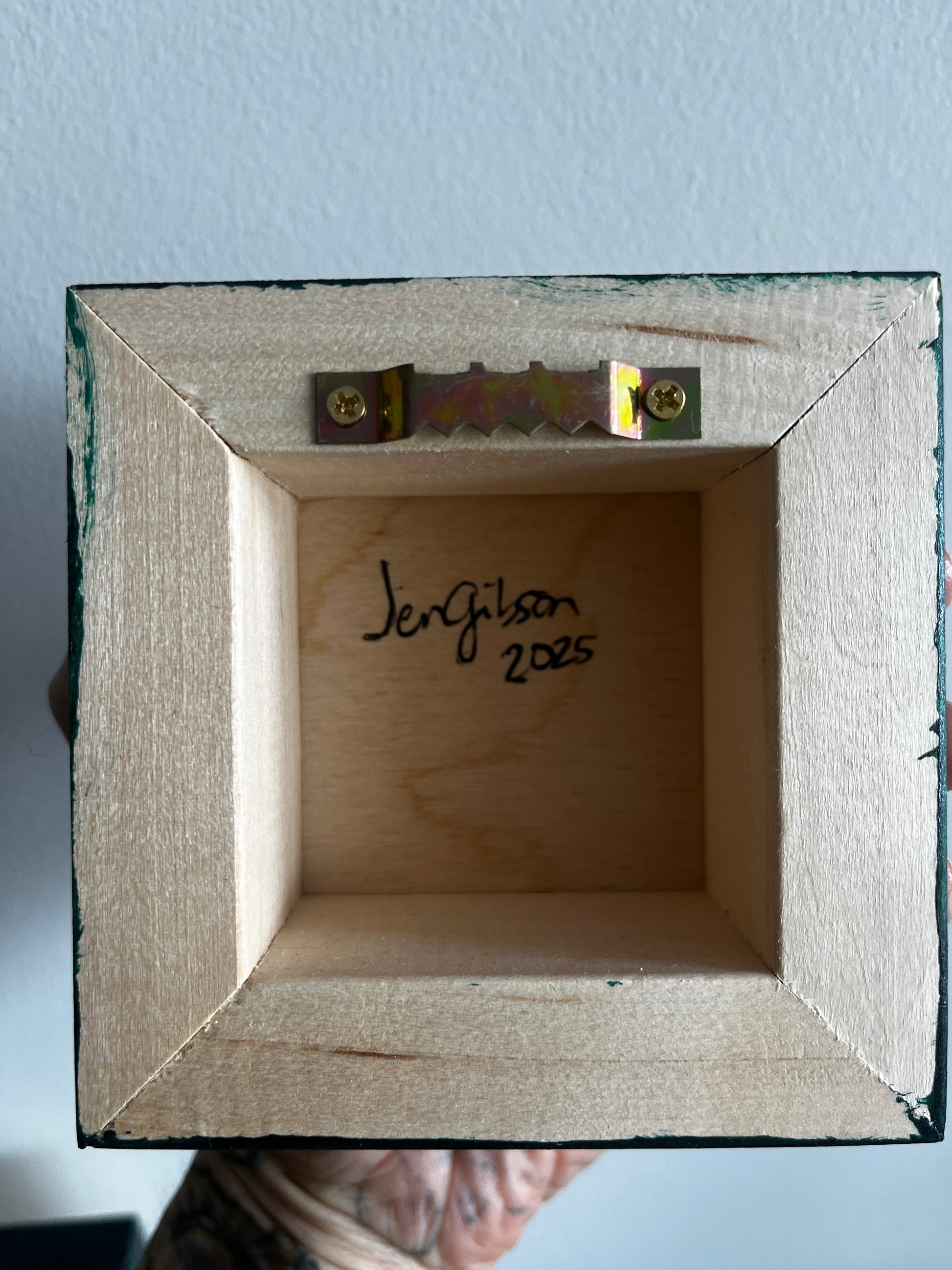 Wooden box with a signature and date on a light blue background