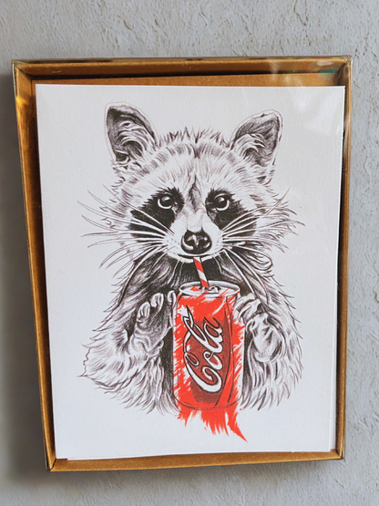 A boxset of notecards with a raccoon holding a drink on a white background