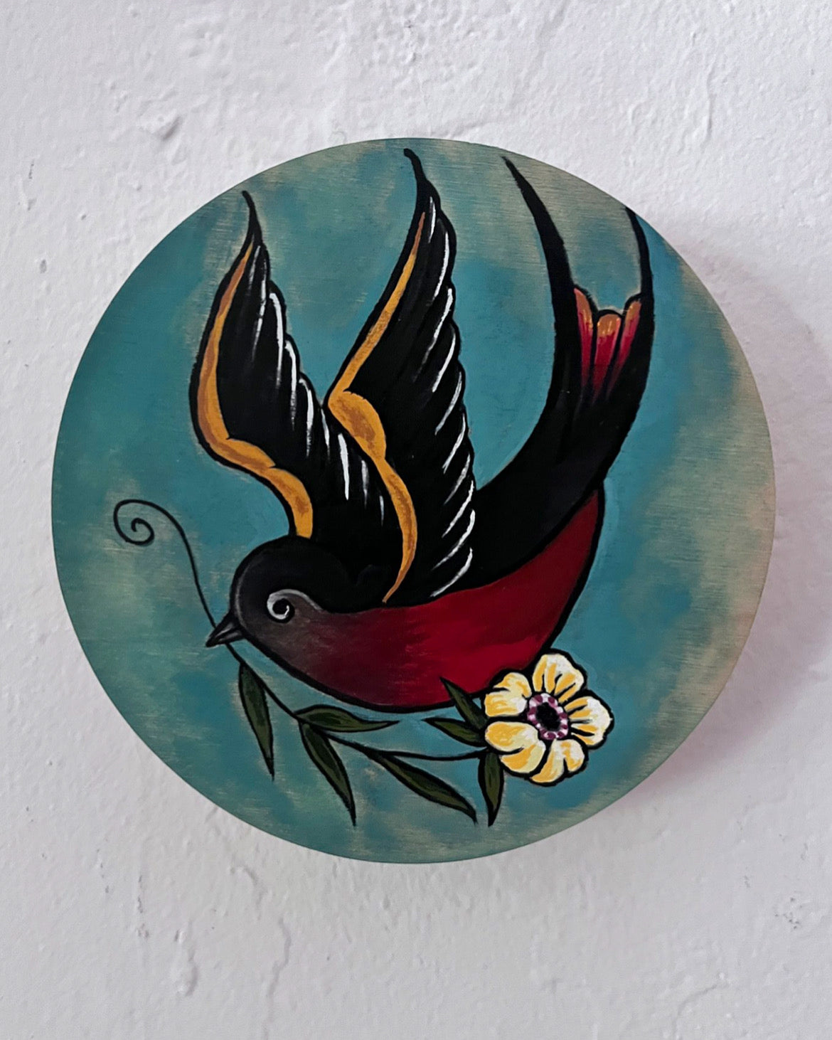Decorative circular piece with a bird and flower design on a textured white background