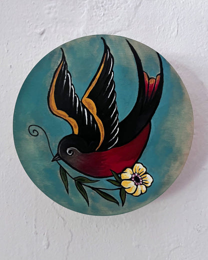 Decorative circular piece with a bird and flower design on a textured white background