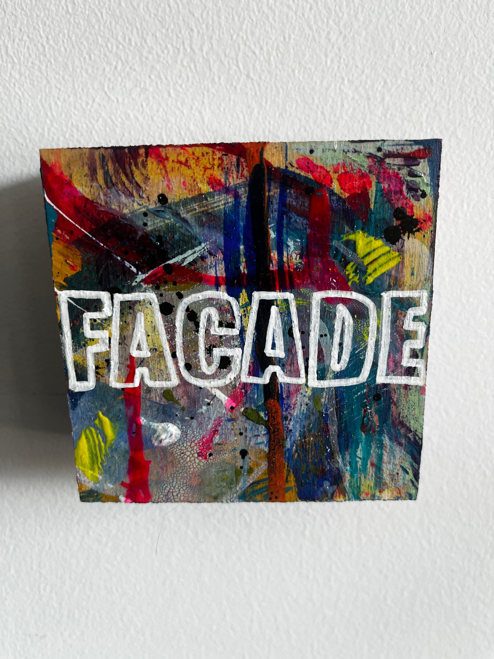 Abstract artwork with colorful patterns and 'FACADE' branding on a white wall.