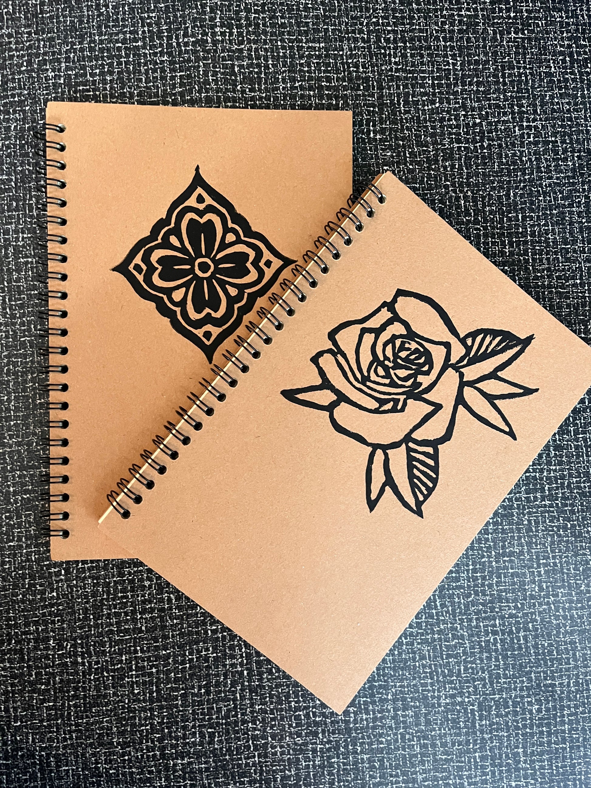 Brown notebook with black floral designs on a textured surface