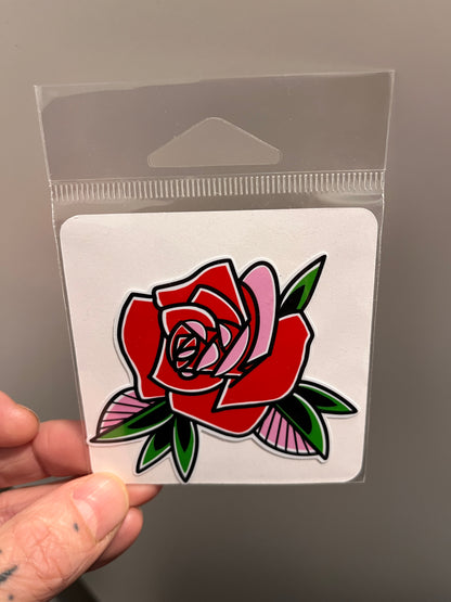 Hand holding a clear plastic card with a red rose sticker.