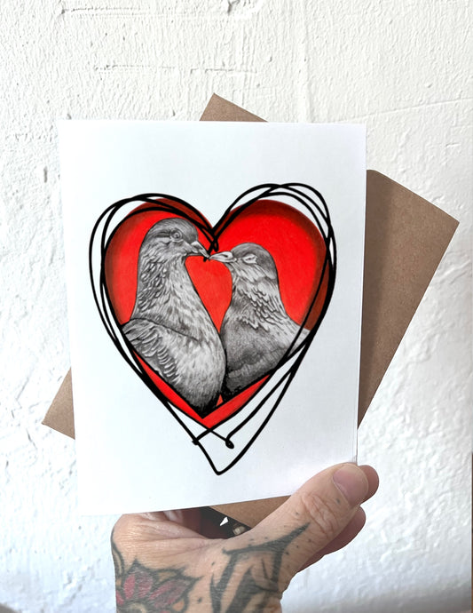 Card with two birds in a heart shape held by a hand against a textured white background