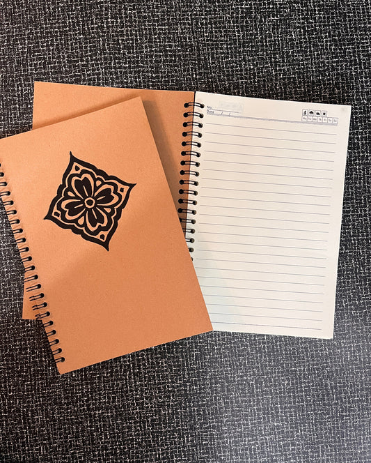 Two notebooks, one with a floral design on the cover, on a textured surface.