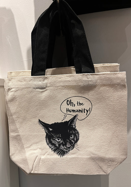 Beige tote bag with black cat illustration and 'Oh, the Humanity!' text on a white background