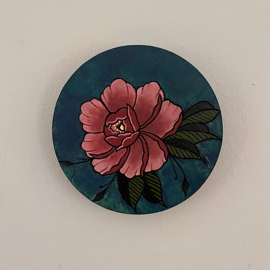 Wooden panel with a pink flower design painted on a dark blue background