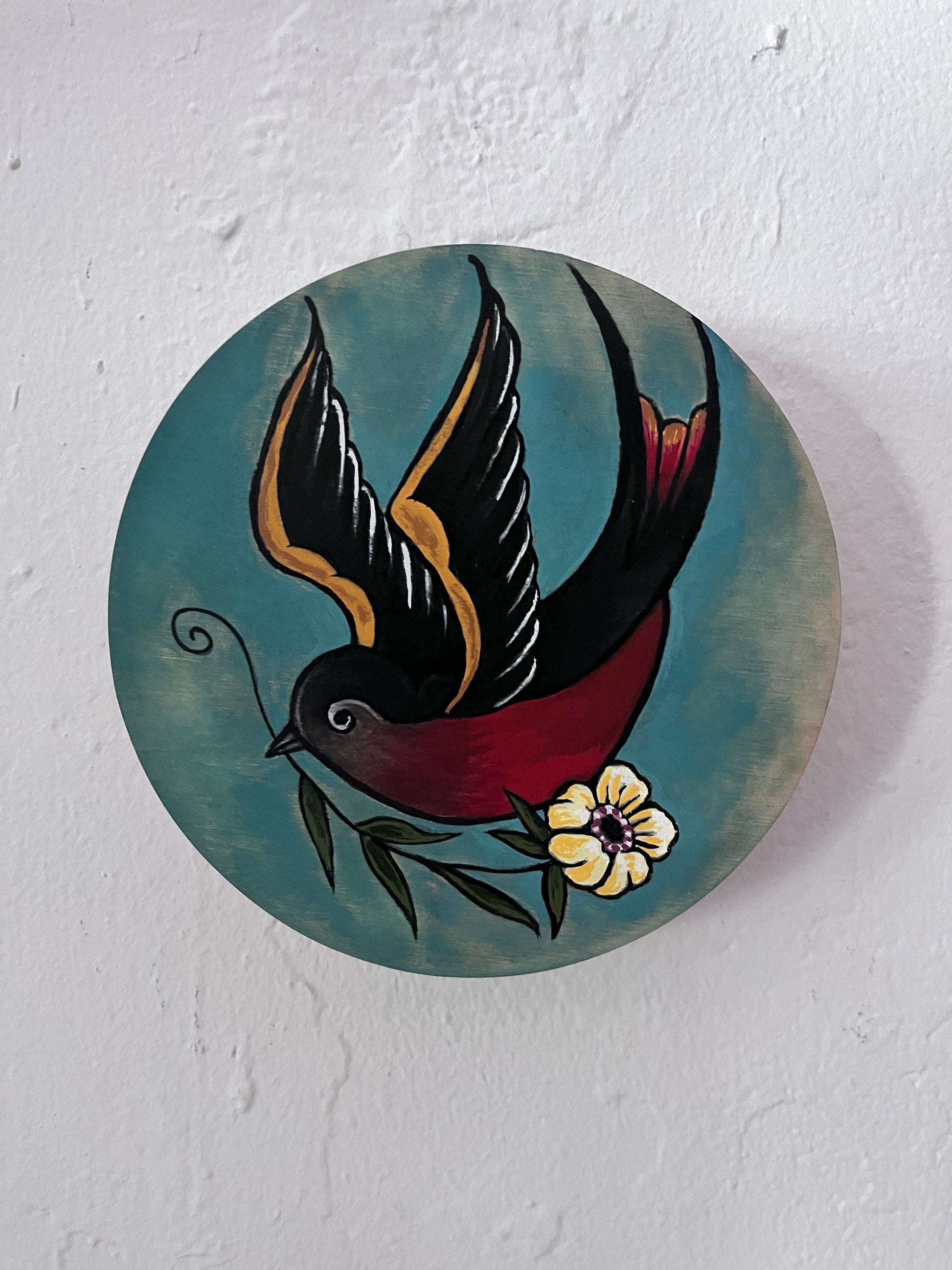 Decorative circular piece with a bird and flower design on a white background