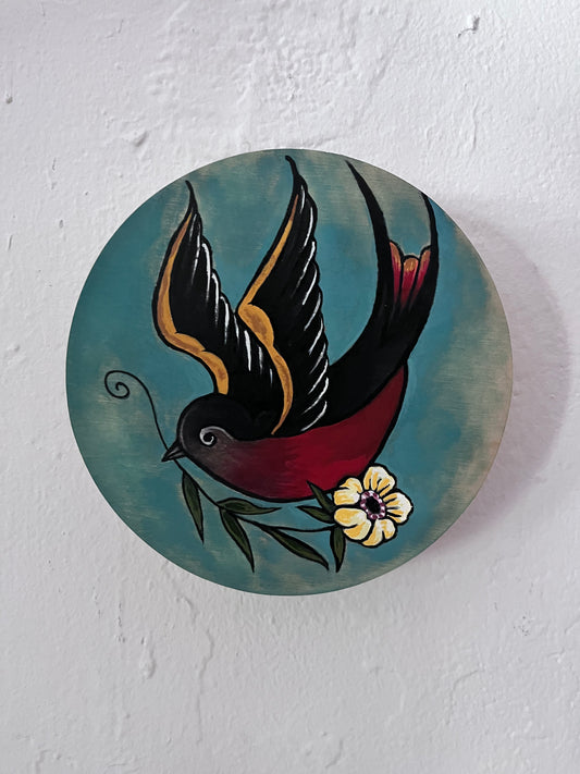 Decorative circular piece with a bird and flower design on a white background