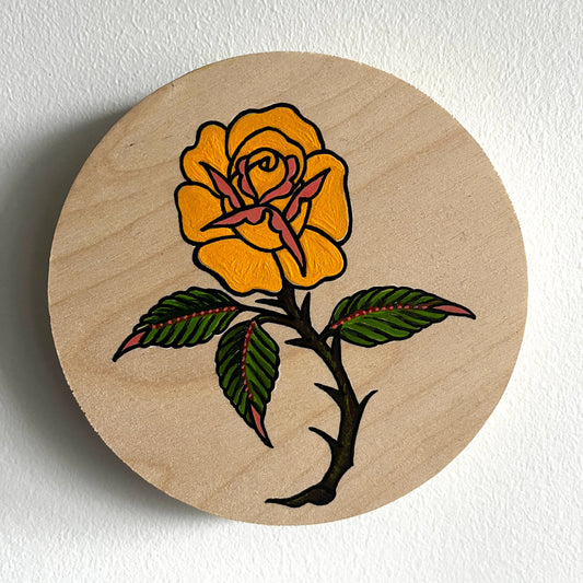 Round wooden painting with a traditional tattoo style yellow long stem rose design on a white background