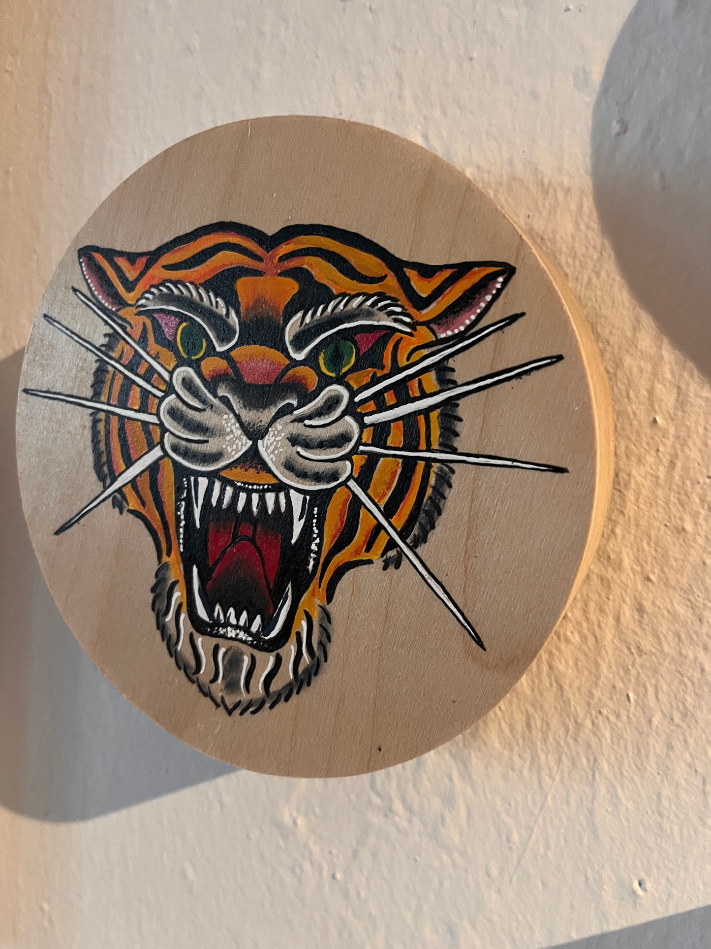 Traditional tattoo style of a tiger painted on a round wooden panel