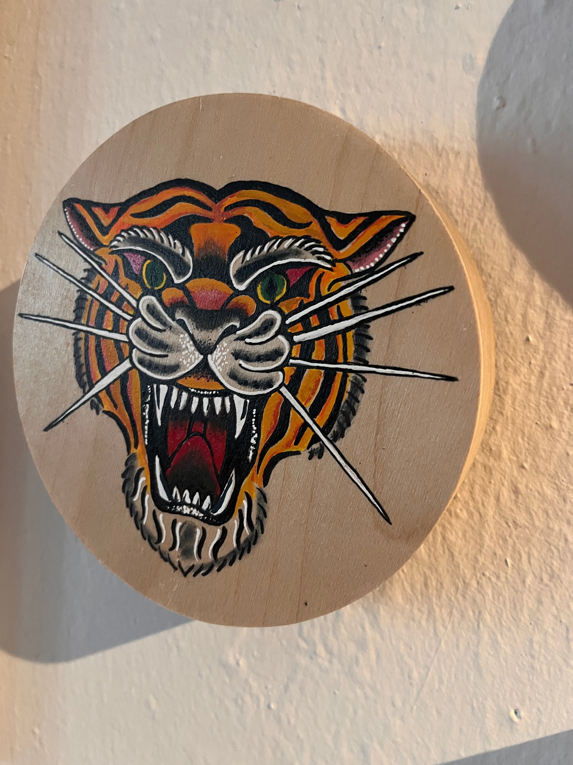 Traditional tattoo style of a tiger painted on a round wooden panel