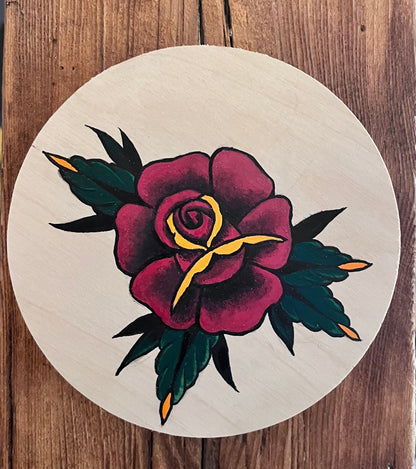Wooden surface with a circular tattoo-style design featuring a rose.