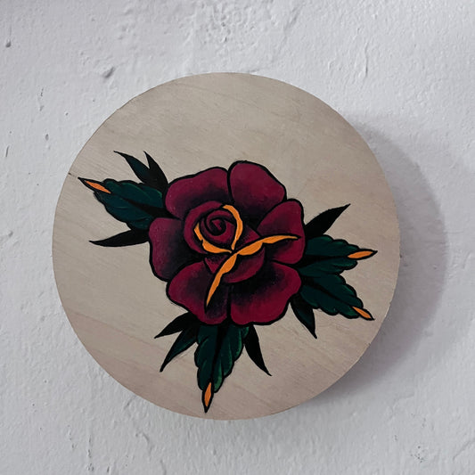 Decorative circular piece with a painted floral design on a textured white background